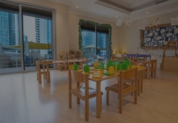 A child’s playroom with wooden tables and chairs.