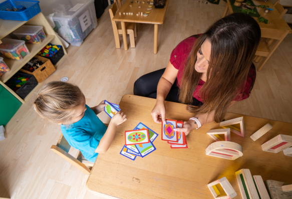 A woman and a child playing with blocks in a classroom.