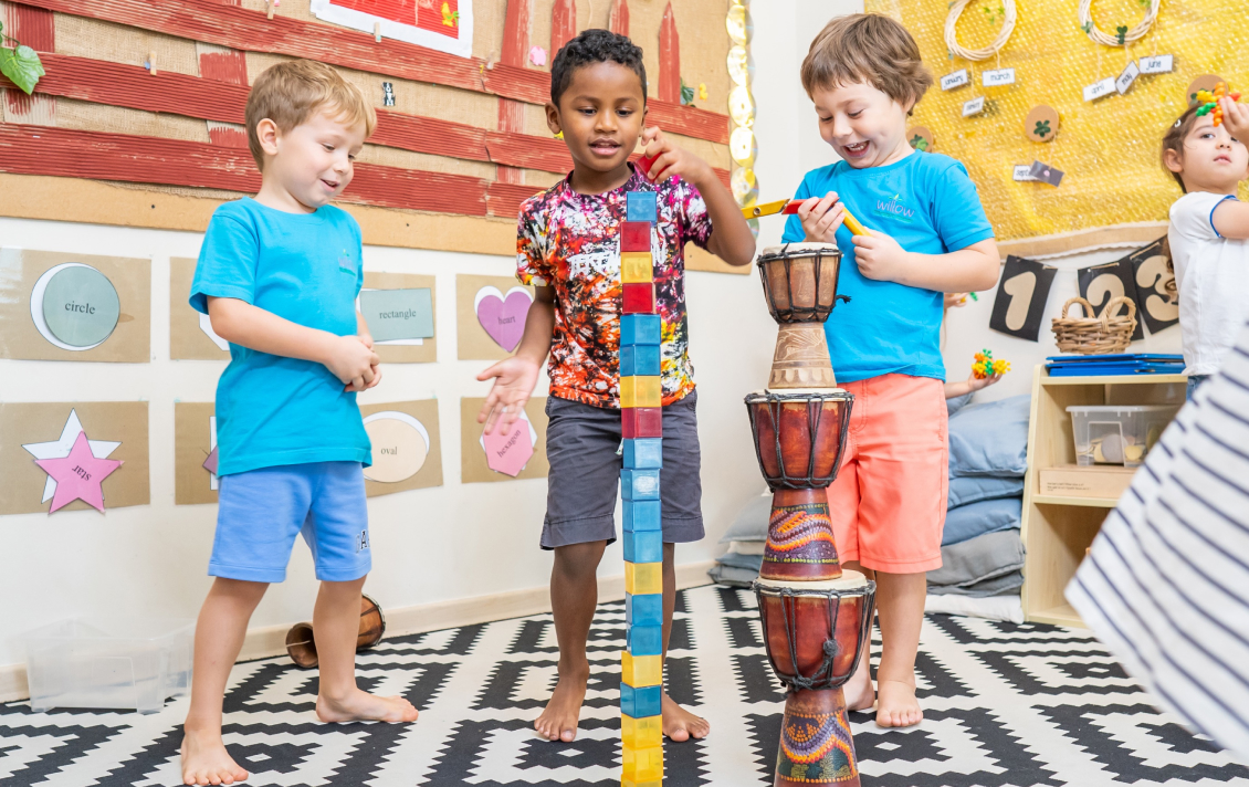 A group of children playing with wooden blocks in a classroom.